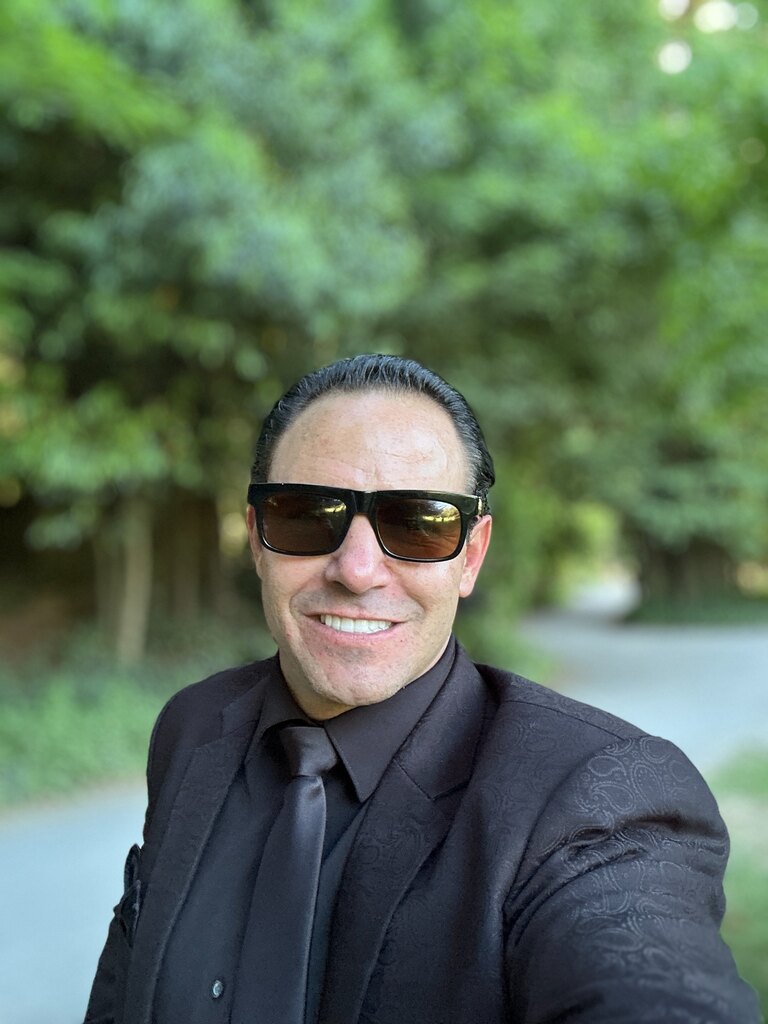 Michael Jannicelli smiling outdoors in a dark suit and sunglasses